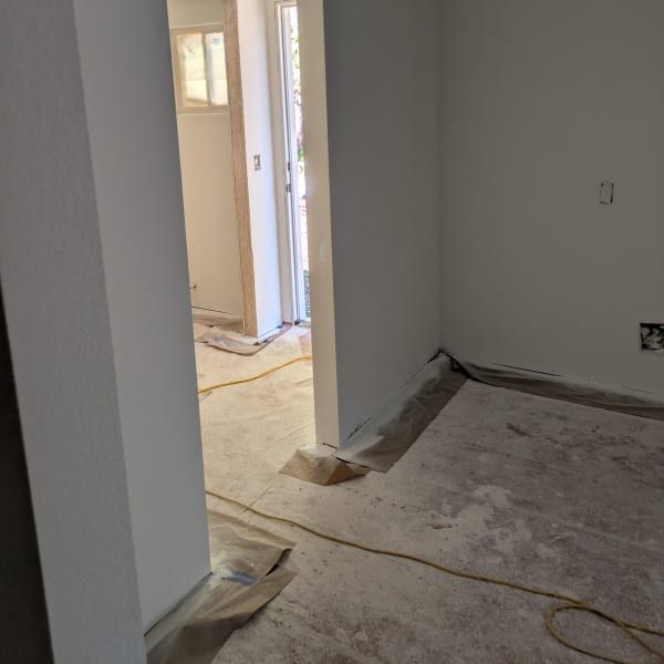 Unfinished interior hallway with white walls, bare floor, and doorway openings under renovation