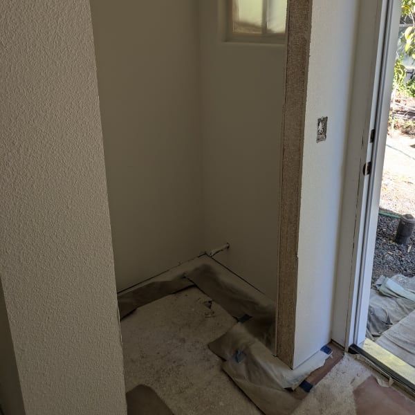 Unfinished closet or alcove with torn flooring and a door opening to an outdoor patio.