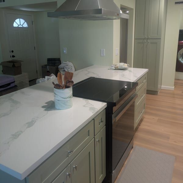 Modern kitchen with white countertops, black island cooktop, and a utensil holder on the counter.