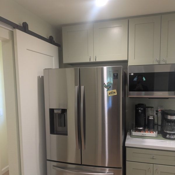 Modern kitchen with a stainless steel refrigerator, built-in microwave, and white cabinets