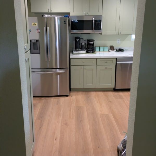 Modern kitchen with stainless steel appliances, light cabinets, and wood flooring