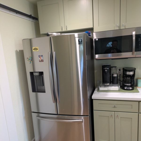 Kitchen with stainless steel refrigerator, microwave, coffee maker, and beige cabinets.