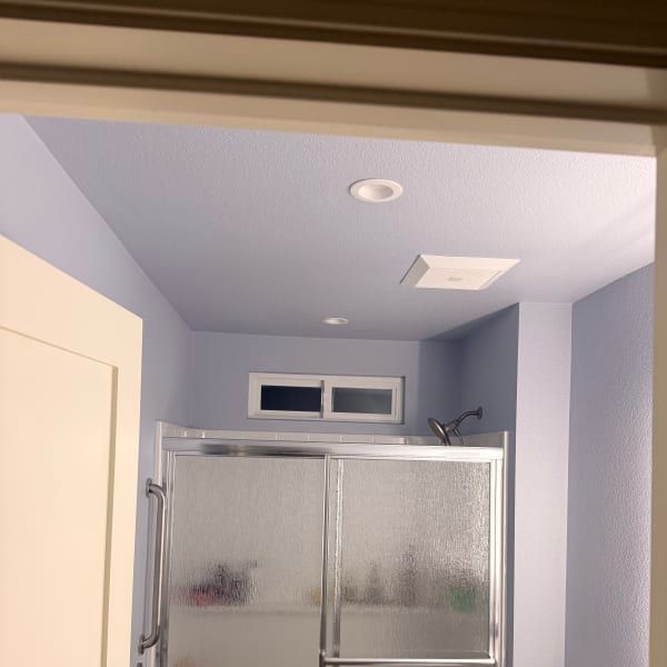 Small bathroom with a frosted glass shower, white door, and light blue walls