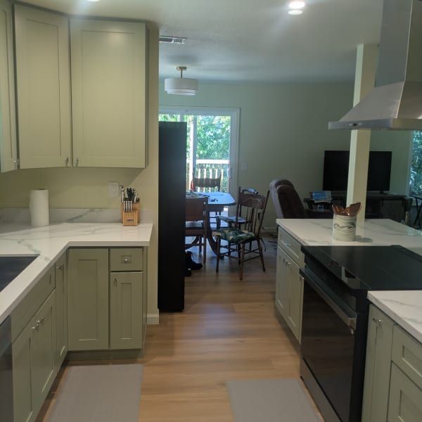 Modern kitchen with white cabinets, island, and view into a dining area with a sliding glass door