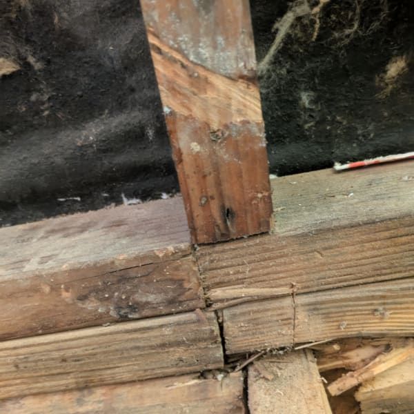 Damaged wooden floorboards and vertical support beam with gaps and wear