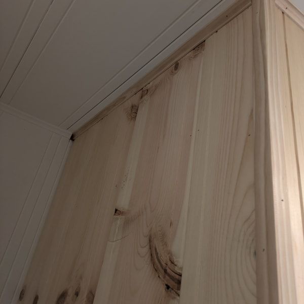 Light pine wood panel wall meeting a white ceiling corner