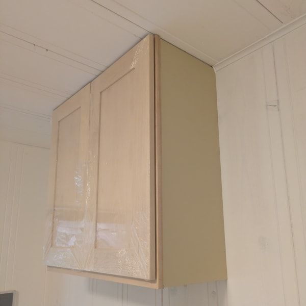 Beige wall-mounted cabinet above a doorway in a white-paneled room.