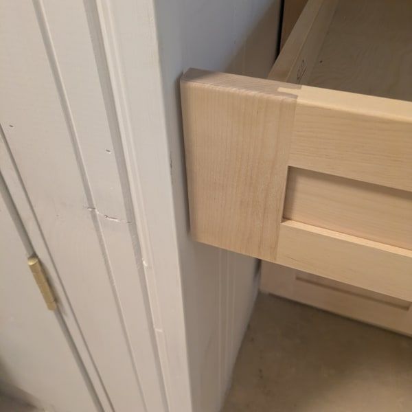 Close-up of a light wood bed frame beside a white wall and beige floor.