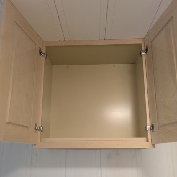 Open wooden kitchen cabinet with both doors open, showing an empty beige interior.