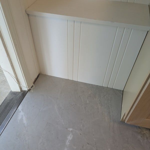White radiator cover in a hallway corner beside a gray tiled floor and doorways