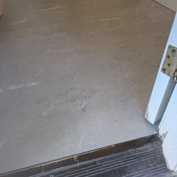 Threshold between a dark floor and a beige floor beside a white doorframe