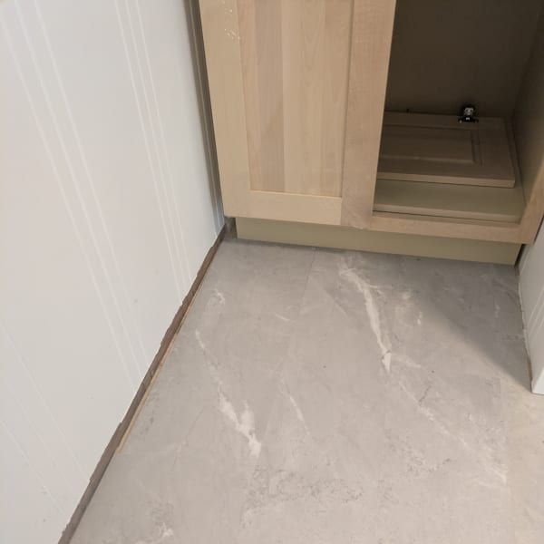 Light wood cabinet beside a white wall on a light gray marble floor.