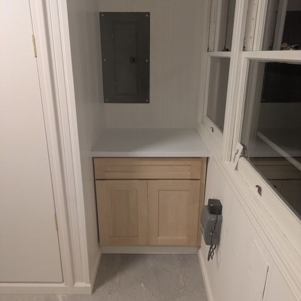 Small bathroom vanity with a light wood cabinet, white walls, and a mirror above it.