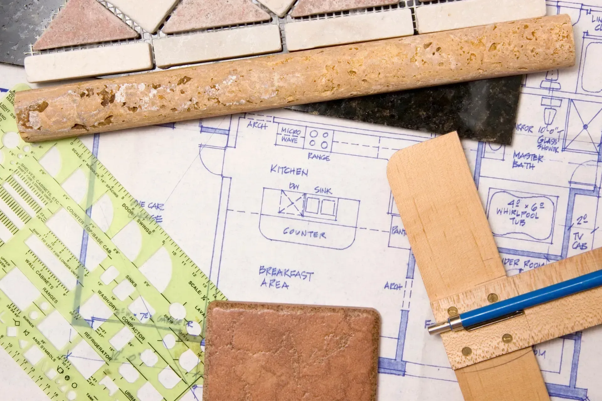 Blueprints with tile samples, cork ruler, and pencil on a drafting table
