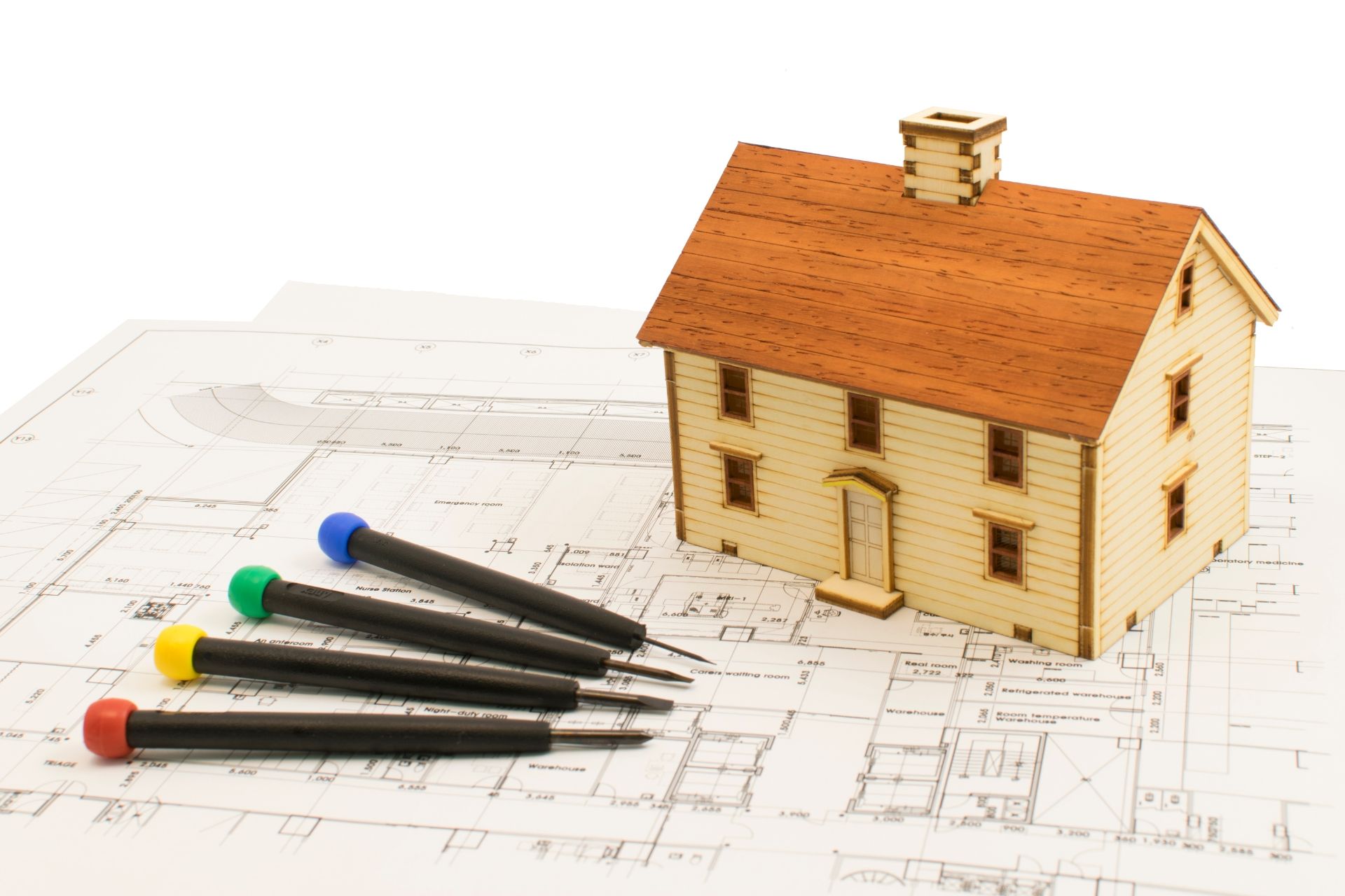 House model on blueprint with four colored pencils nearby