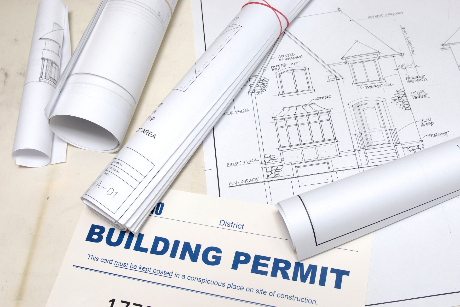 Permit document with rolled blueprints on architectural plans.