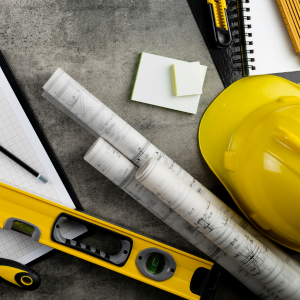 Construction tools, ruler, level, tape measure, and yellow hard hat on a gray surface