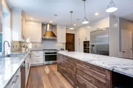 Modern kitchen with sage cabinets, stainless appliances, white countertops, and a window over the sink.