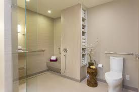Modern bathroom with glass shower, toilet, beige tile, and decorative vase lighting