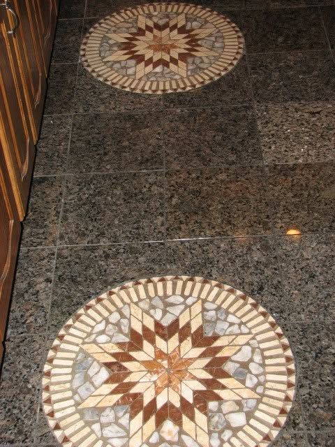 Polished dark granite floor with two round decorative mosaic medallions in tan, brown, and cream
