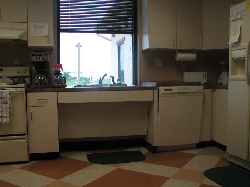 Small kitchen with white cabinets, sink under a window, and checkered floor tile.