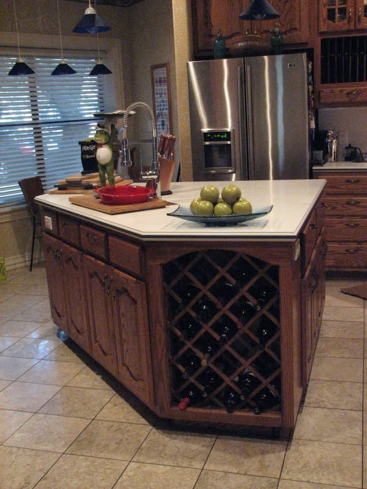 Kitchen island with fruit bowls, wine rack, stainless fridge, and pendant lights in a tiled home kitchen