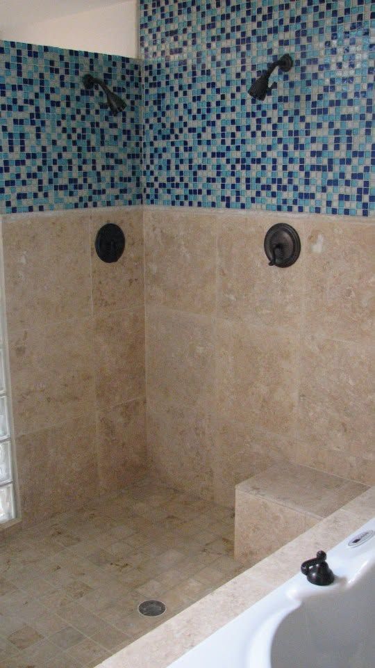 Tiled shower with beige walls, blue mosaic accent, and built-in bench.