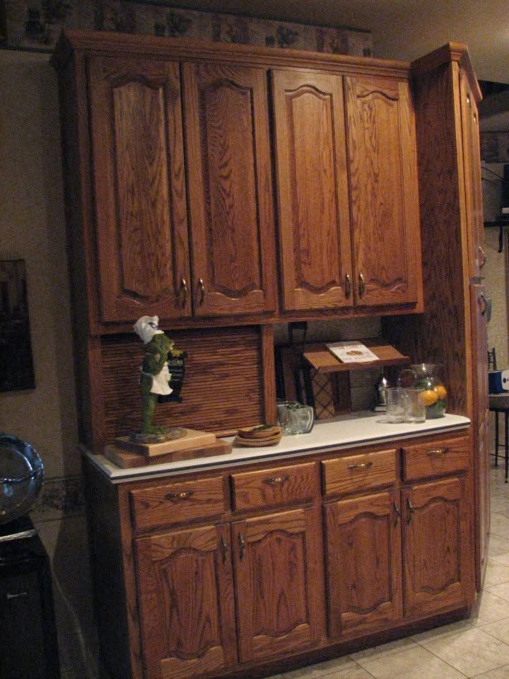 Wooden kitchen cabinet wall with lower storage and countertop, in a dimly lit room