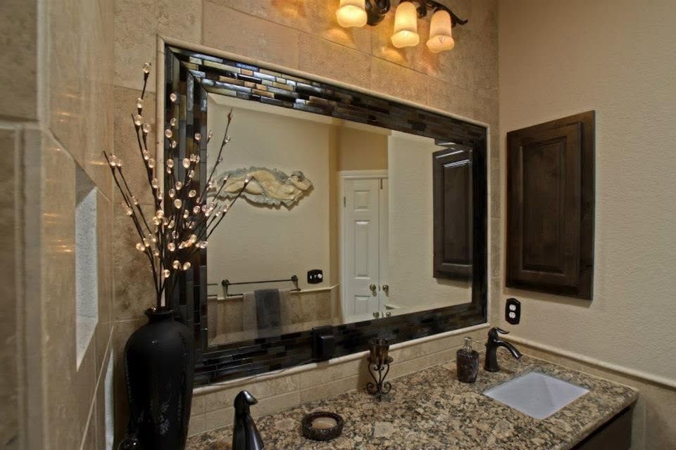 Bathroom vanity with granite counter, large mirror, sink, and decorative vase with lit branches