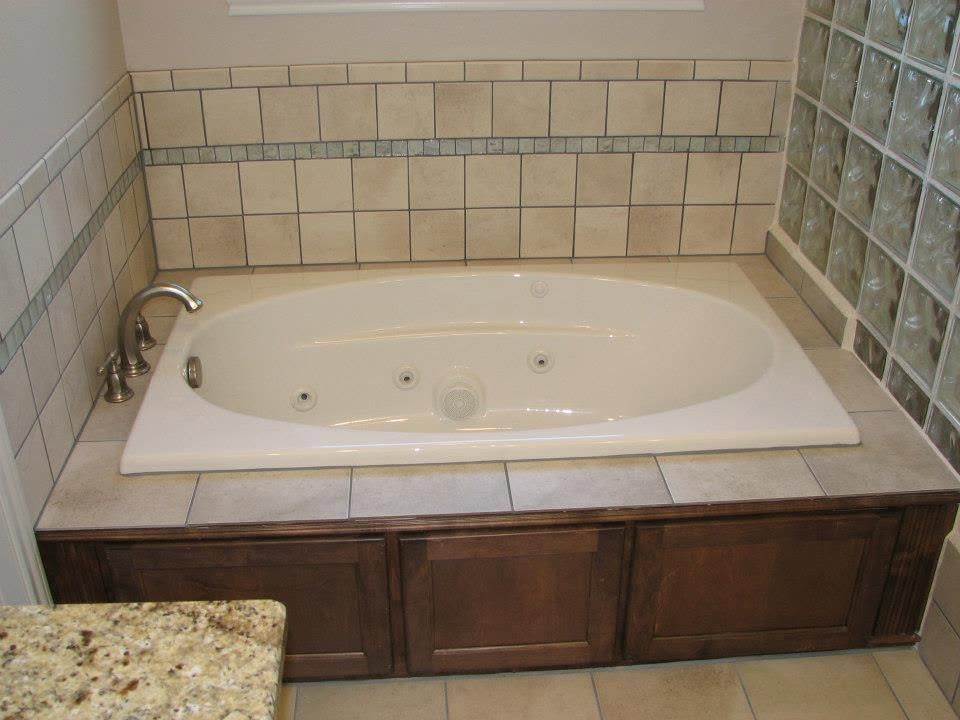 Built-in bathtub with tiled surround and dark wood cabinetry in a bathroom