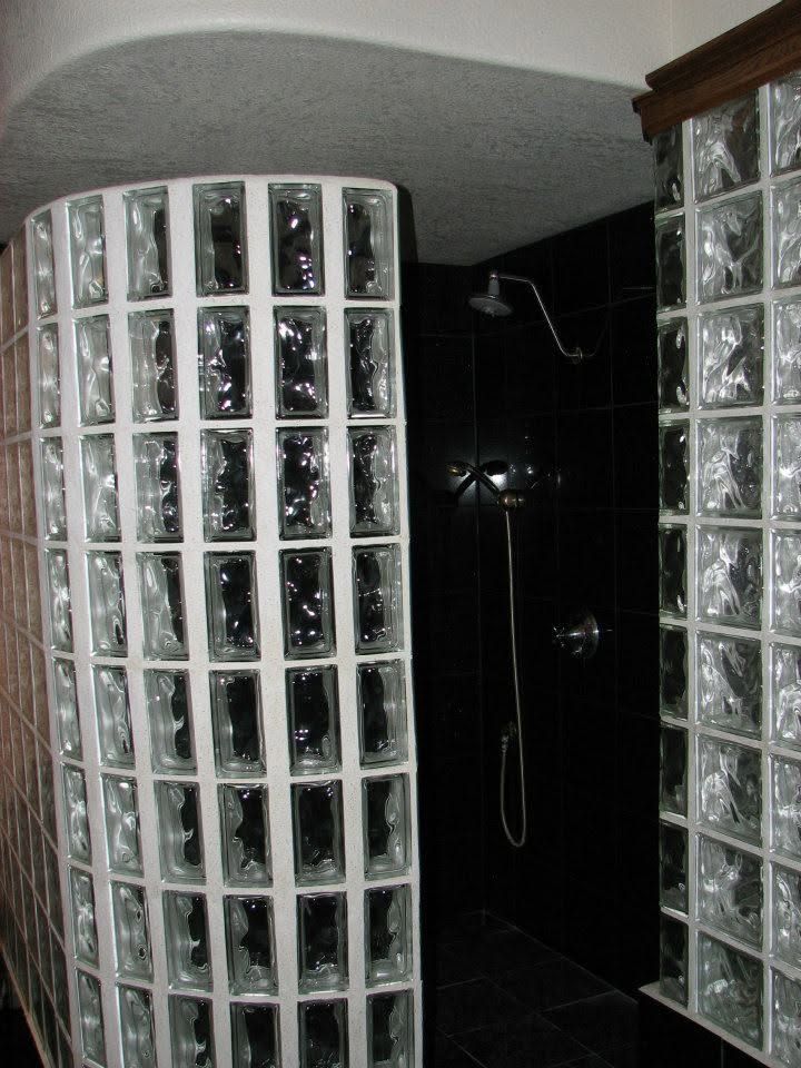 Curved glass-block shower enclosure with black tile wall and chrome shower fixtures