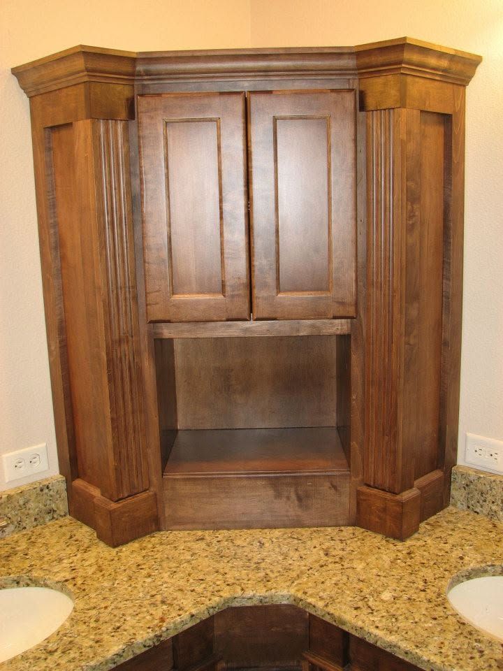 Wooden bathroom vanity with cabinets and open sink space on a granite countertop.