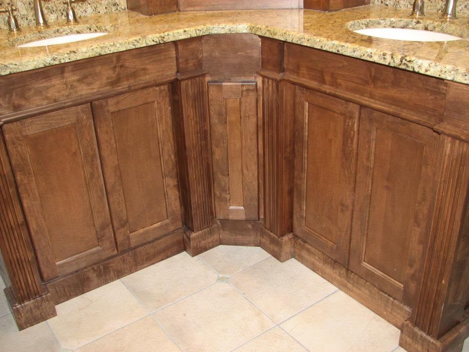 Corner wooden kitchen cabinets with granite countertop and beige tile floor