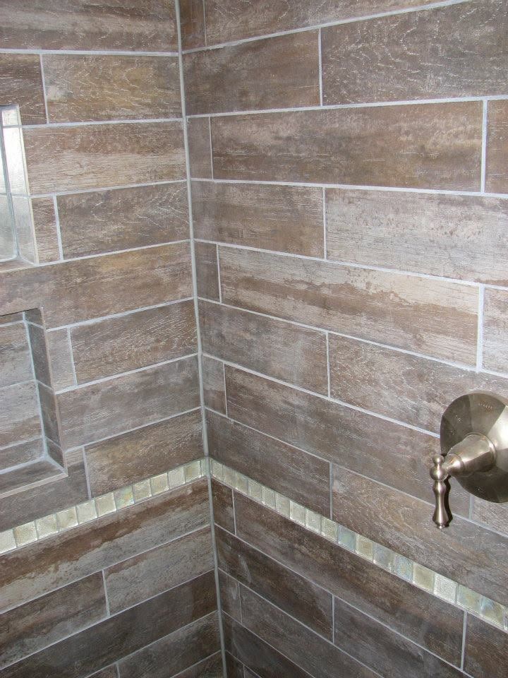 Corner of a tiled shower with a chrome fixture on the right.