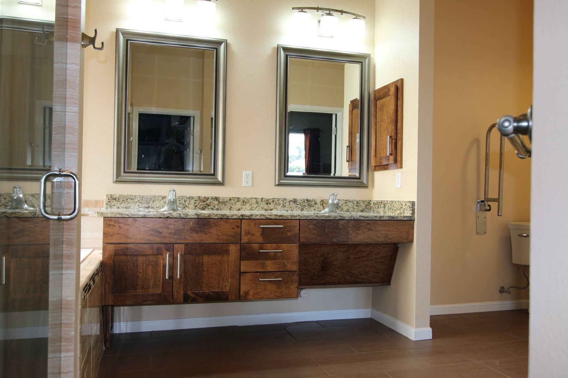 Bathroom vanity with double mirrors, granite countertop, and dark wood cabinets in a beige tiled room