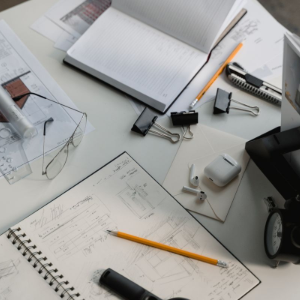 Architectural workspace with blueprints, sketchbook, pencils, a ruler, and a desk lamp