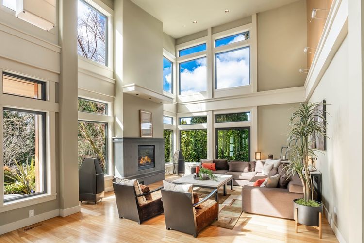 Bright, airy living room with tall windows, fireplace, and modern seating around a central coffee table.
