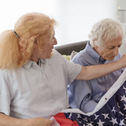 Two older women folding an American flag on a couch in a bright living room