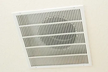 White rectangular air vent on a white ceiling.