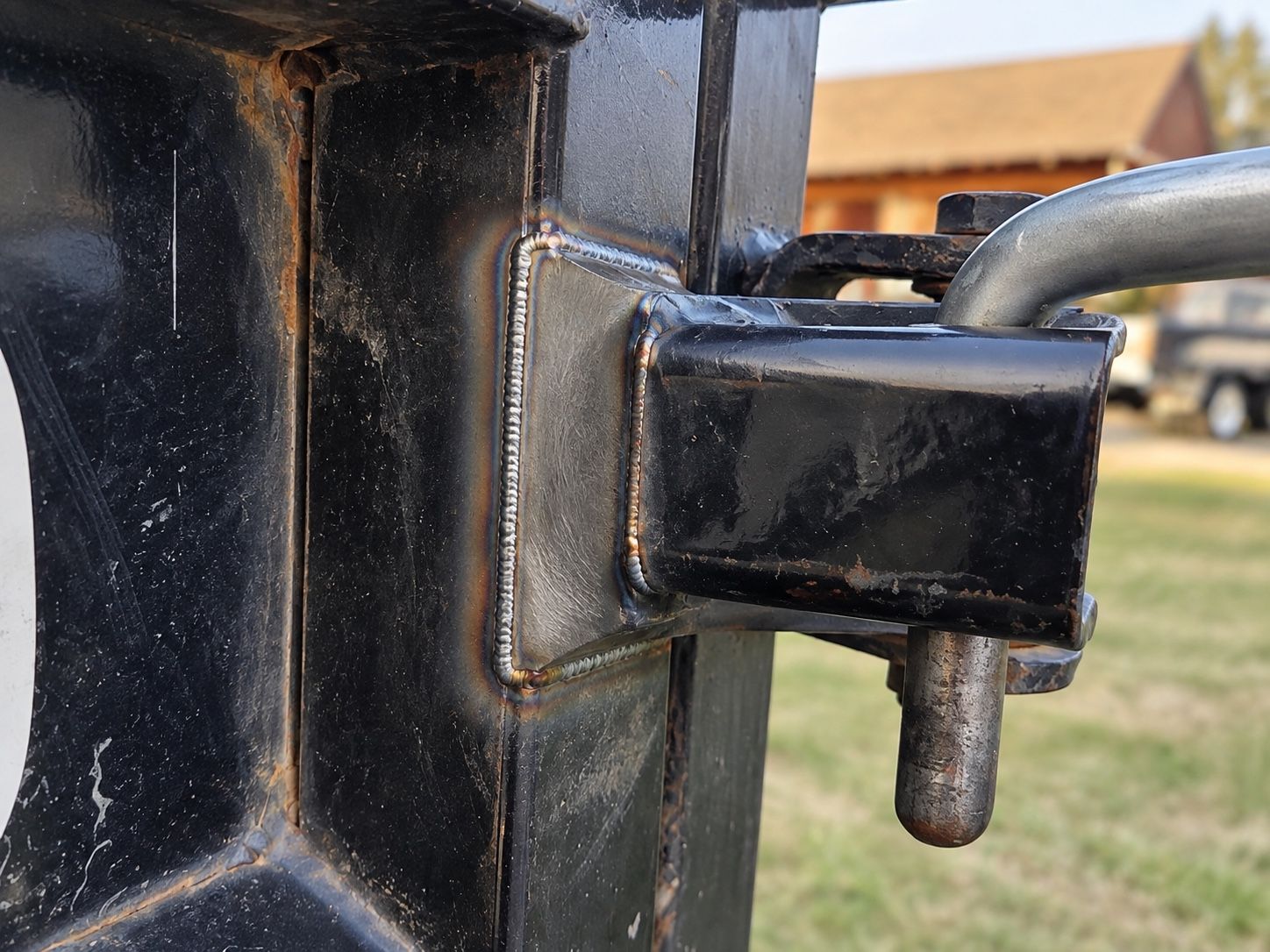 Close-up of a black metal trailer hitch latch with a gray pin on a vehicle hitch.