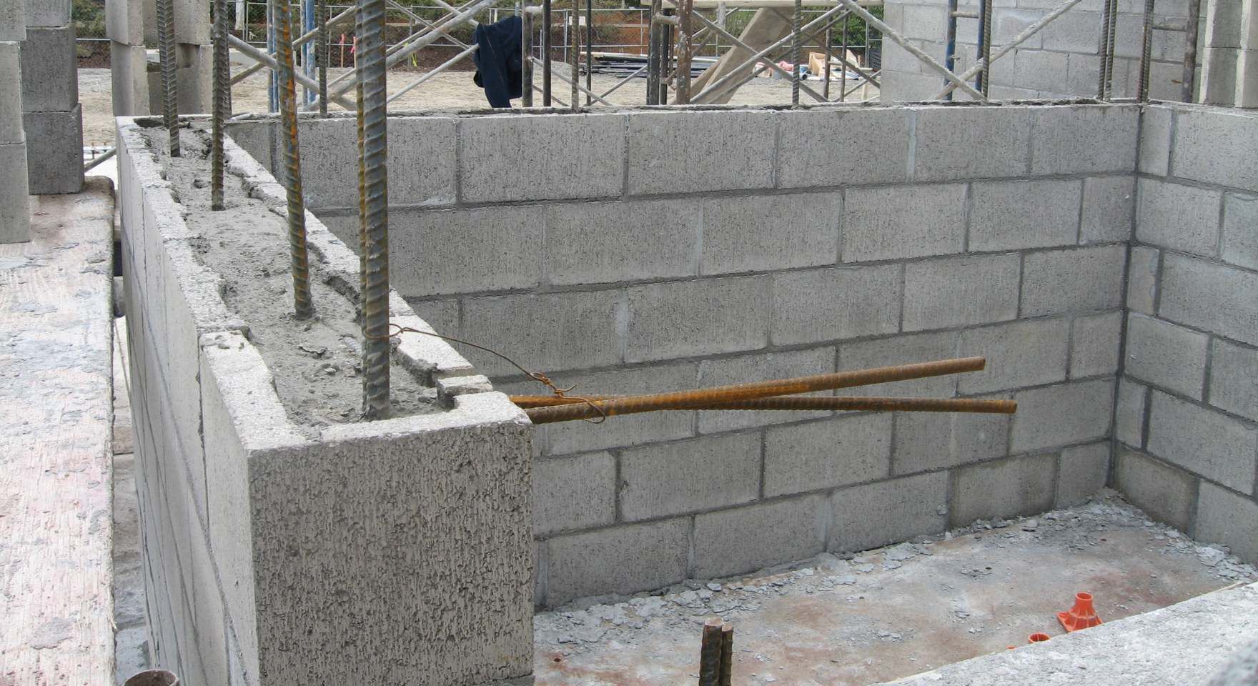 Partially built concrete block retaining wall with rebar and construction layout lines in Irvine, CA