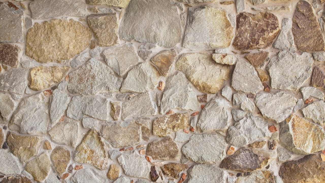Close-up of a natural stone wall with varied tan and gray rocks during block and retaining wall services in Orange, CA