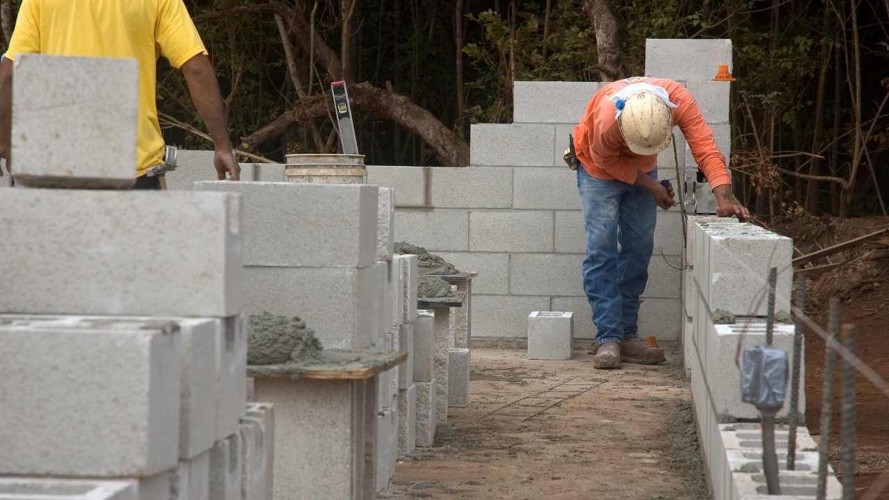 Worker building a concrete block retaining wall with stacked blocks and fresh mortar in Tustin, CA