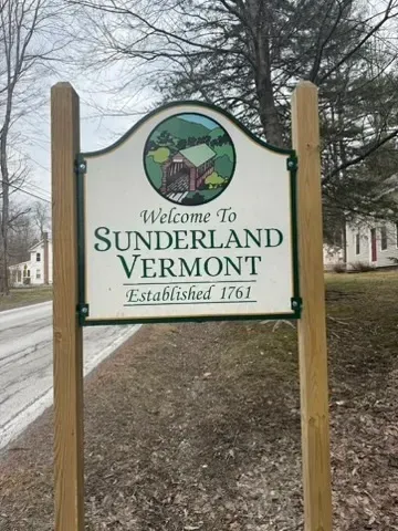 Welcome sign for Sunderland, Vermont, between wooden posts on a roadside