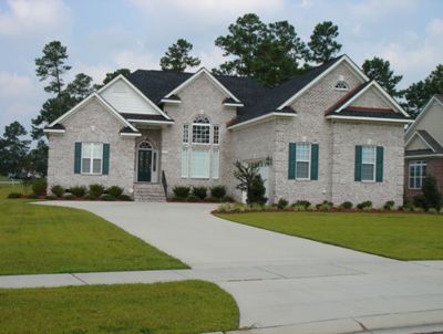 A large white brick house with green shutters