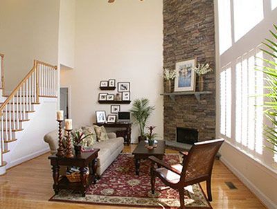 A living room with a couch , chair , coffee table and stairs.