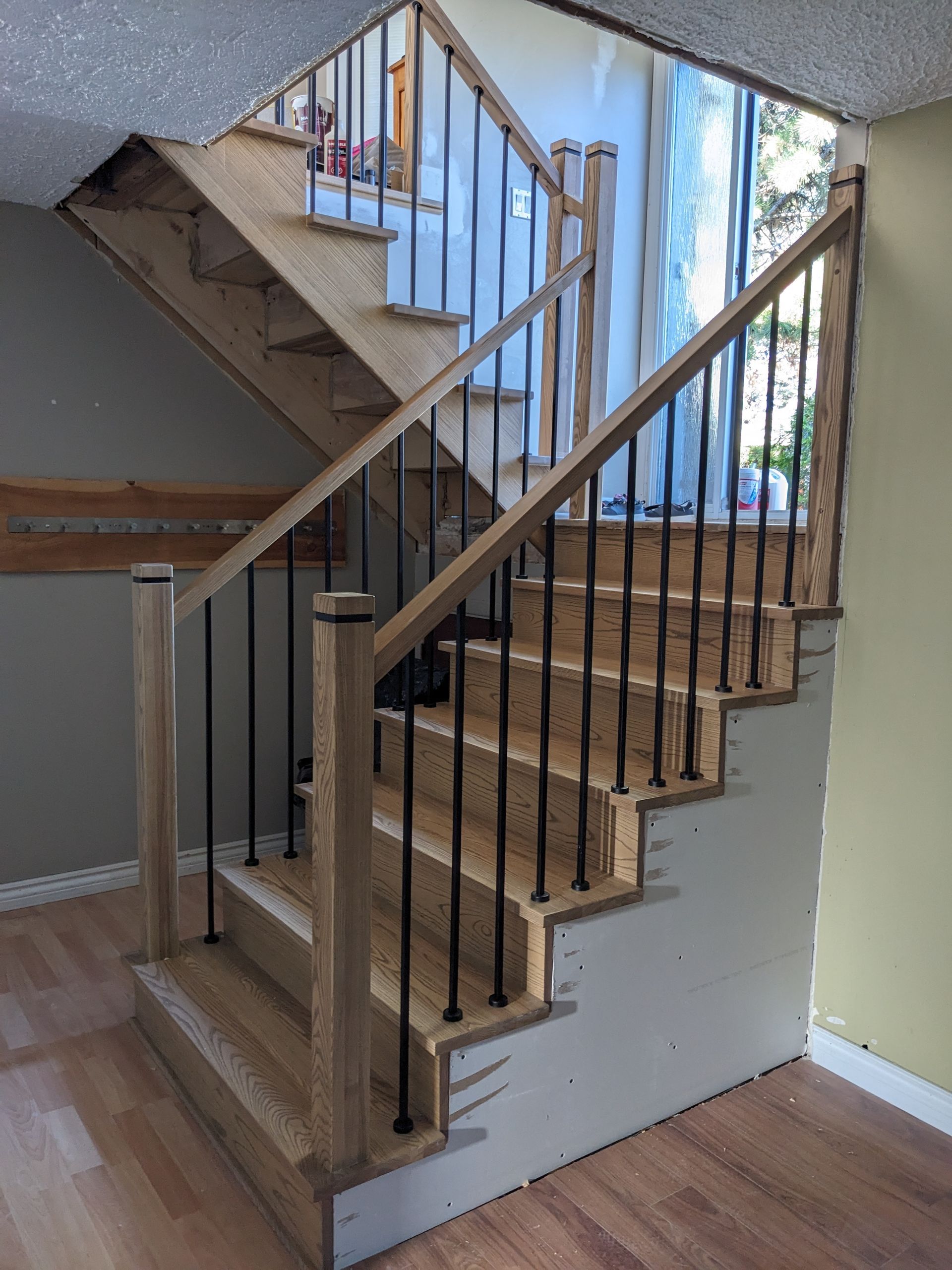 Escalier en bois avec balustres en métal noir ; construction en cours.