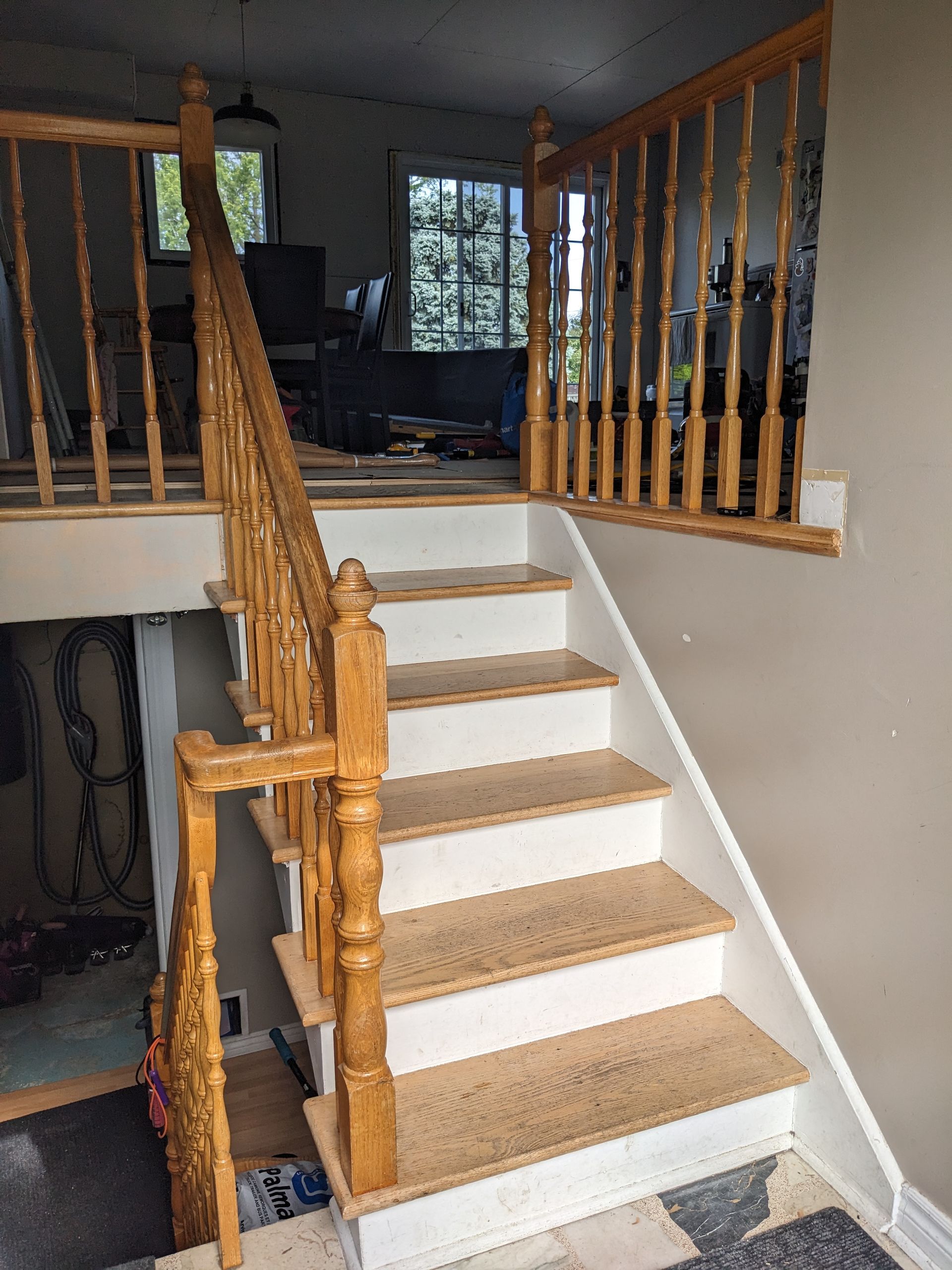 Escalier en bois avec contremarches blanches, menant à un palier et à une porte ouverte.