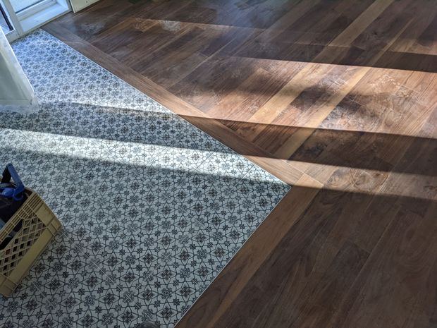 Sol composé de carreaux à motifs et de lames de bois disposées en diagonale ; lumière naturelle.