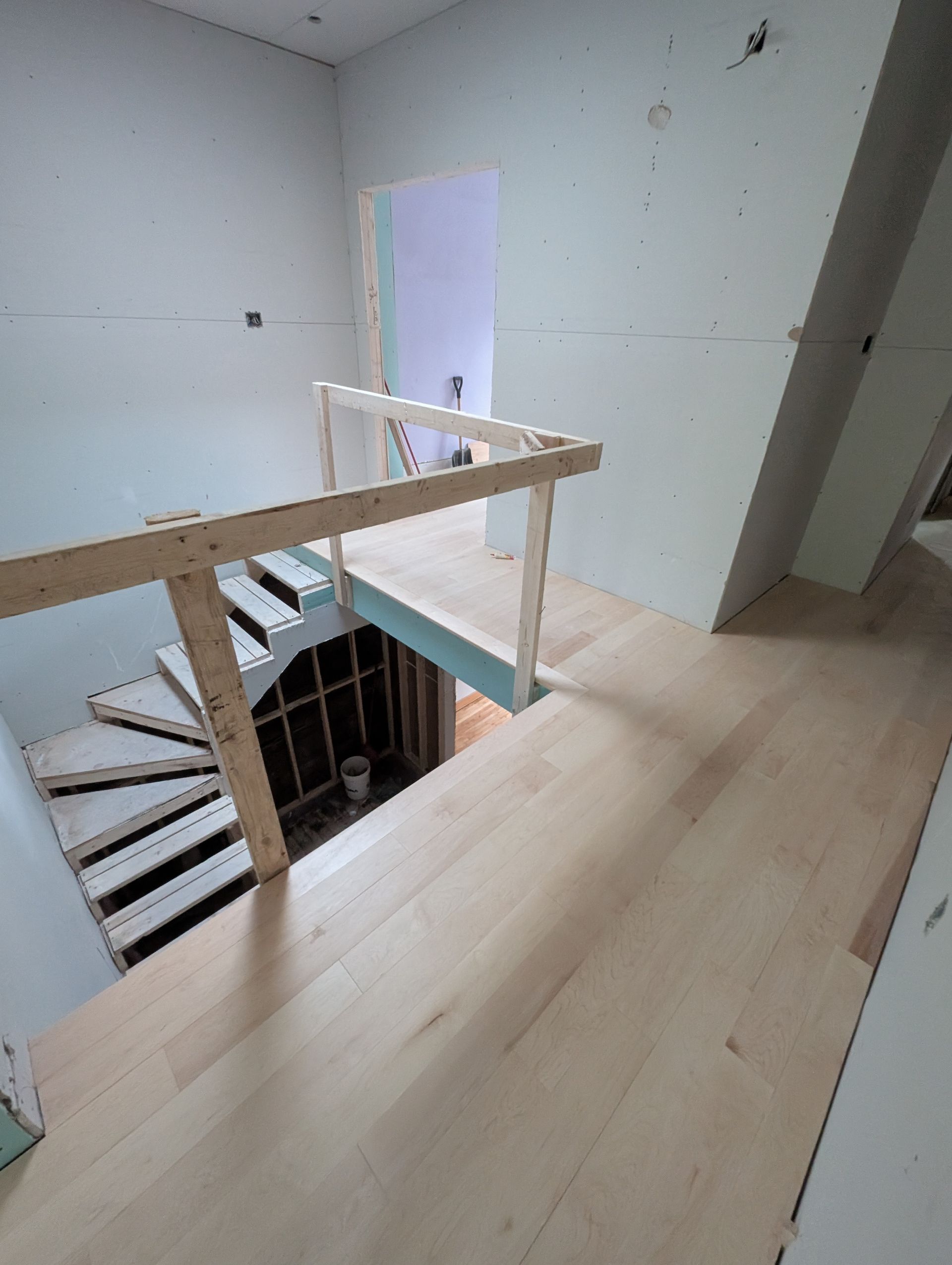 Vue intérieure d'un chantier de construction avec un escalier en bois et des murs inachevés.